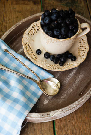 Fresh blueberries in vintage bowl and bright napkin on old wooden tableの写真素材