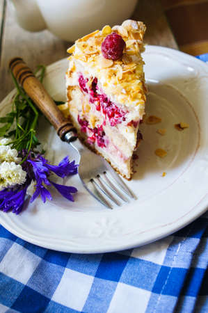 Almond cake with Raspberries on the plate and summertime flowersの写真素材