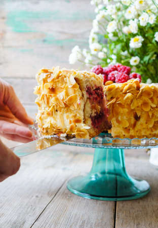Almond cake with Raspberries on the plate and summertime flowersの写真素材