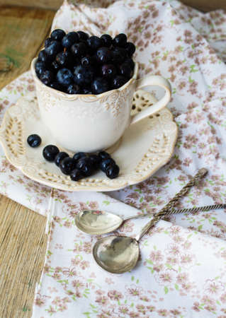 Fresh blueberries in vintage bowl and bright napkin on old wooden tableの写真素材