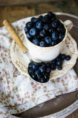 Fresh blueberries in vintage bowl and bright napkin on old wooden table