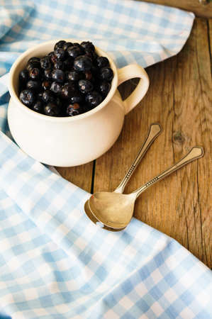 Fresh blueberries in vintage bowl and bright napkin on old wooden tableの写真素材