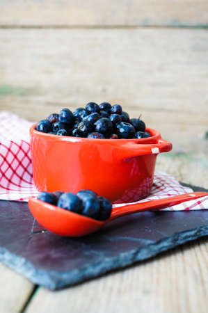 Fresh blueberries in vintage bowl and bright napkin on old wooden tableの写真素材