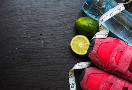 Sport shoes, measuring tape, lime and water on black backgroundの写真素材