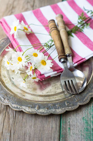 Summertime Table Setting with daisy flowers, napkin and silverware on wooden tableの写真素材
