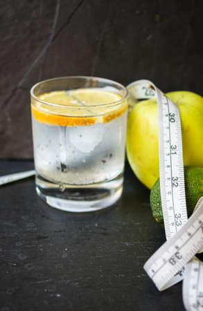 Glass of water with lime and green apple on the black stone backgroundの写真素材