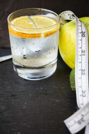 Glass of water with lime and green apple on the black stone backgroundの写真素材