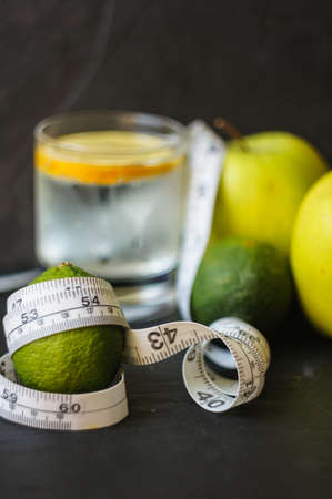 Glass of water with lime and green apple on the black stone backgroundの写真素材
