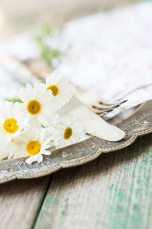 Summertime Table Setting with daisy flowers, napkin and silverware on wooden tableの写真素材