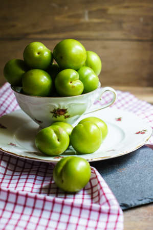 Green cherry-plum in vintage bowl, selective focusの写真素材