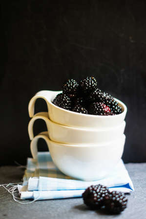 Fresh blackberry fruits in the bowl on old wooden tableの写真素材