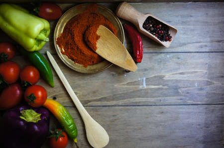 Ripe fresh vegetable cherry tomatoes, bell and chilli peppers, onion and pepper spices, rustic backgroundの写真素材