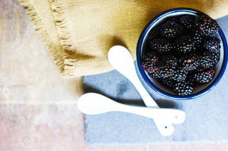 Fresh blackberry fruits in the bowl on old wooden tableの写真素材