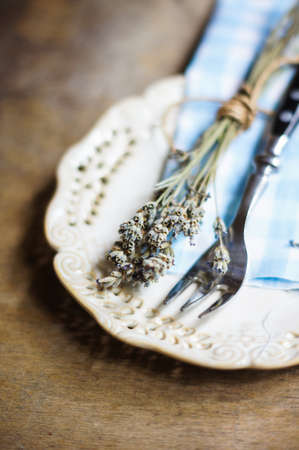 Rustic Table Setting with napkin, silverware and dry lavendre lowers on old wooden table