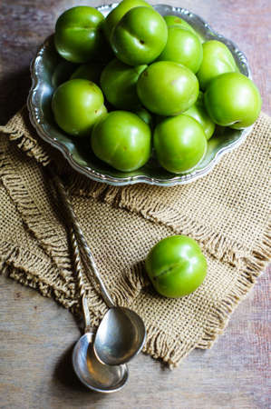 Green cherry-plum in vintage bowl, selective focusの写真素材