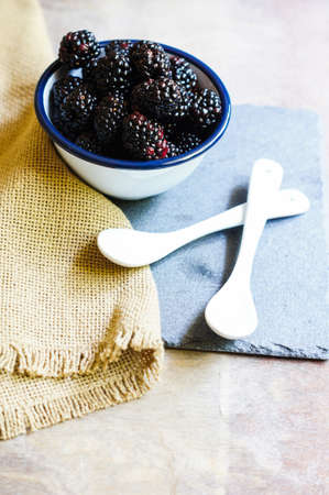 Fresh blackberry fruits in the bowl on old wooden tableの写真素材