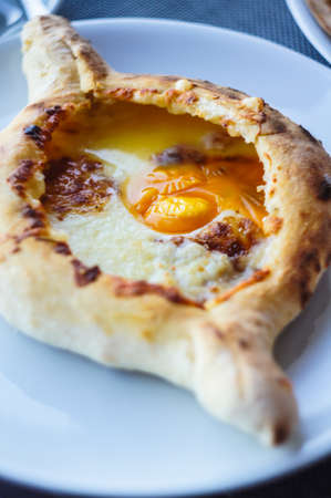 Ajarian or Adjaruli khachapuri, filled with cheese and topped with a raw egg and butter - traditional dish of georgian cuisineの写真素材