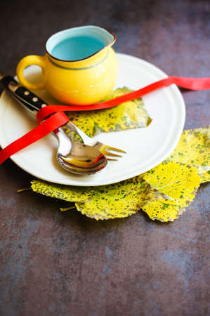 Autumnal table setting with vintage table silverware and yellow leavesの写真素材