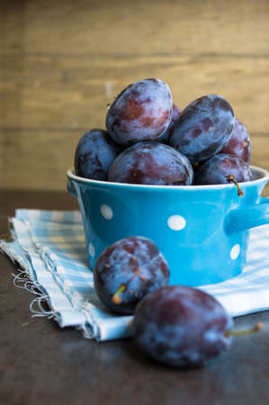 Plate full of fresh plums on a wooden background.の写真素材