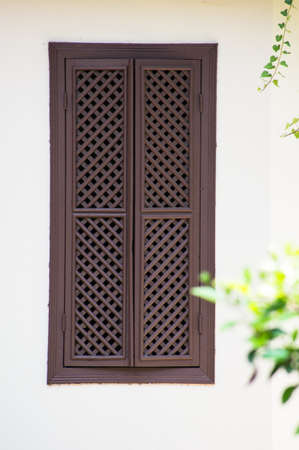 Window with brown  shutters on bright white wallの写真素材