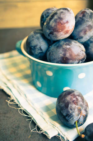 Plate full of fresh plums on a wooden background.の写真素材