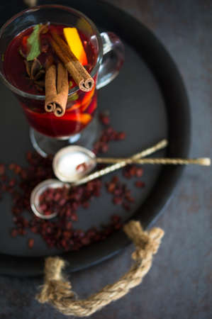 Mulled wine with spices on wooden background