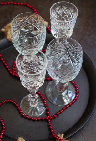 Vintage crystal glasses on the black tray with christmas decorations. Selective focus