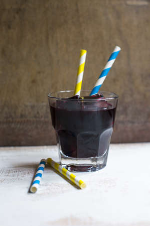 Vintage glass of mulled wine with straws on the old wooden background