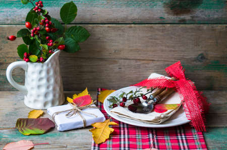 Rustic autumnal table setting with yellow leaves and berriesの写真素材