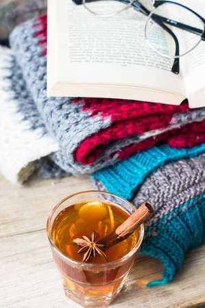Cup of tea with ginger and spices with book and glasses on bright colors scarf  on the rustic backgroundの写真素材