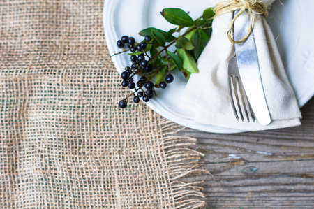 Rustic autumnal table setting with yellow leaves and berries