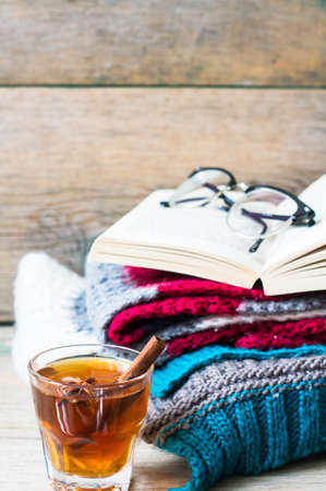 Cup of tea with ginger and spices with book and glasses on bright colors scarf  on the rustic...