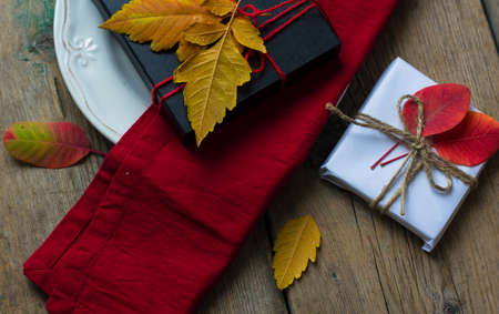 Rustic autumnal table setting with yellow leaves and berries