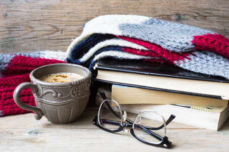 Cup of tea with ginger and spices with book and glasses on bright colors scarf  on the rustic backgroundの写真素材