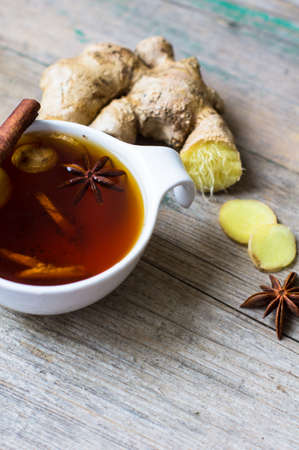 Cup of tea with ginger, cinnamon sticks and anise star spice on the rustic background