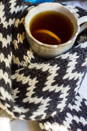 vintage cup of tea with lemon surrounded knitted stripped scarfの写真素材