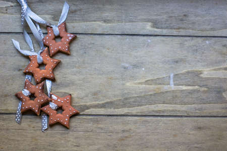 Gingerbread cookies star shaped hanging on the ribbon over wooden backgroundの写真素材