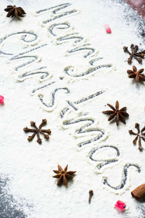 Handwritten words Merry Christmas on flour with holiday spices as a decorationの写真素材