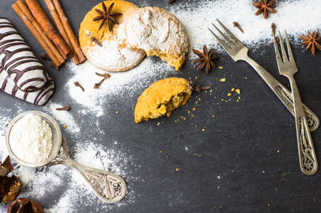 Christmas sweet cookies with vintage silverware, spices and flour on the black stone backgroundの写真素材