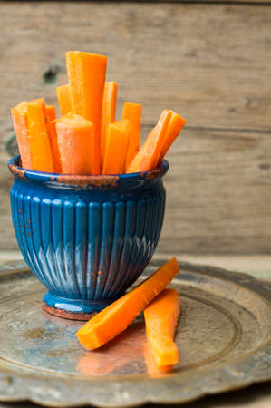 Diet food fresh carrot sticks in vintage bowl on the rustic wooden backgroundの写真素材