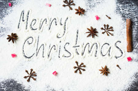 Handwritten words Merry Christmas on flour with holiday spices as a decorationの写真素材