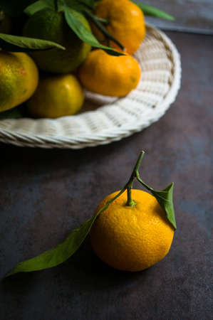 Ripe tangerines with green leaves on dark rustic backgroundの写真素材