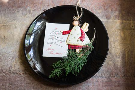Christmas table setting with vintage silverware and angel decorations on rustic plateの写真素材