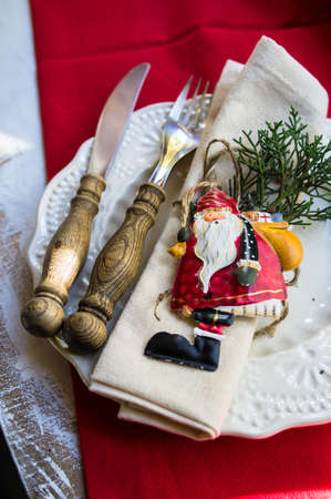 Christmas table settinf with vintage silverware and Santa decorations on rustic plate