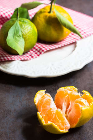 Ripe tangerines with green leaves on dark rustic backgroundの写真素材