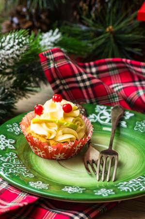 Christmas time decorations with festive decorated cupcake on the plate on rustic backgroundの写真素材
