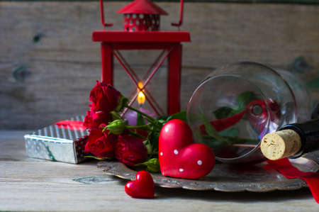 Table setting for St. Valentines day with glasses of red wine, present box and red roses  in rustic styleの写真素材