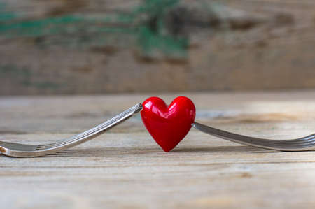 Red heart between two vintage forks on rustic wooden backgroundの写真素材