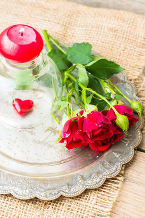 Table setting for St. Valentines day with glasses of wine, present box and red roses  in rustic styleの写真素材