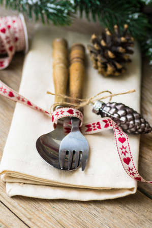 Christmas table setting with vintage silverware and pine tree branch in vase and blue christmas...